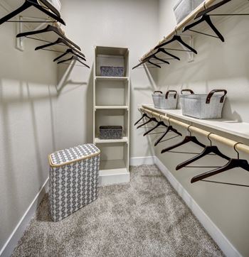 A white closet with a trash can and hangers.